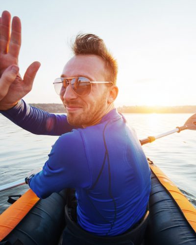 man floating on lake in a kayak at fantastic sunset.